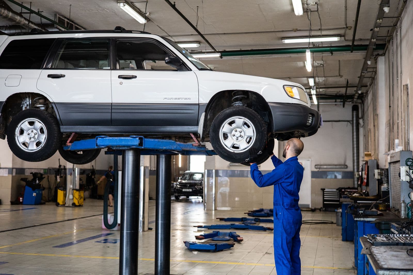 Automotive technician inspecting a vehicle in a workshop